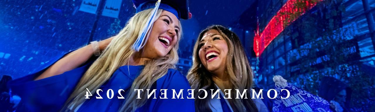 two graduates in blue cap and gowns smiling